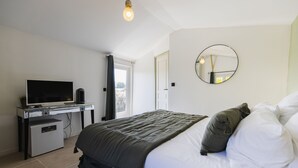 Une chambre avec un lit, une télévision, un petit réfrigérateur et une fenêtre avec des rideaux.