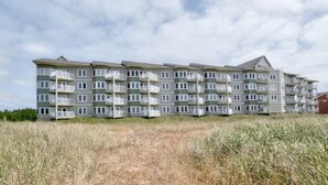 A multi-story residential building with balconies, located in a grassy area. - 2bd, 2ba, Walk to Town and Beach (SRetreat) (Long Beach)