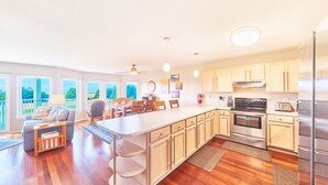 A spacious kitchen with wooden cabinets, a large island, and a dining area with chairs and a table. - 2bd, 2ba, Walk to Town and Beach (SRetreat) (Long Beach)