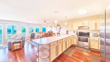 A spacious kitchen with wooden cabinets, a large island, and a dining area with chairs and a table.