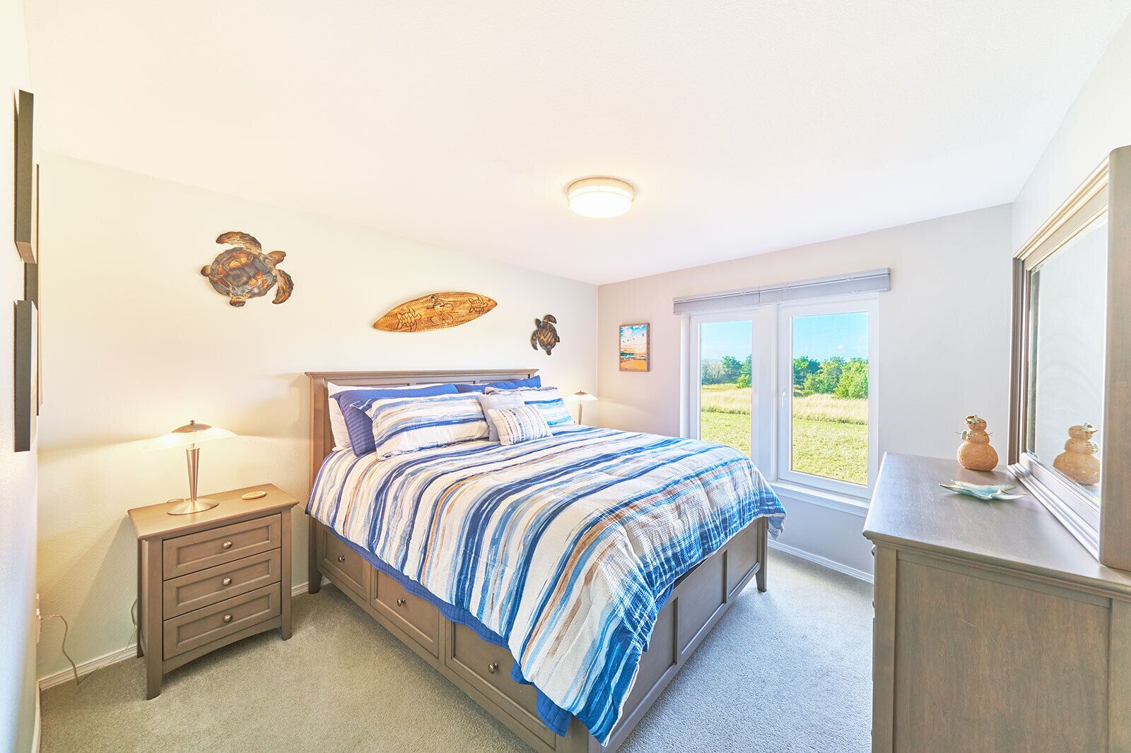 Une chambre à coucher comprenant un lit, des tables de chevet, une commode et une fenêtre donnant sur un paysage verdoyant.