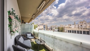 A balcony with two grey chairs, a small table, and a decorative floral arrangement. - Luxury 3-Bedroom Apartment Athens Nea Smirni (ΝΕΑ ΣΜΥΡΝΗ)