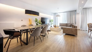 A modern living room with a dining area, a sofa, and a TV. - Luxury 3-Bedroom Apartment Athens Nea Smirni (ΝΕΑ ΣΜΥΡΝΗ)