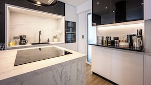 A modern kitchen with a marble countertop, black and white cabinetry, and a built-in oven. - Luxury 3-Bedroom Apartment Athens Nea Smirni (ΝΕΑ ΣΜΥΡΝΗ)