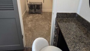 A compact bathroom with a white chair, a towel rack, and a small table with a towel.