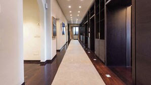 A long, narrow hallway with a carpeted floor, recessed lighting, and a dark wooden door on the right. - Luxury Lungarno House by MMega (Florence)
