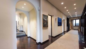 A modern hotel hallway with a marble floor, a staircase, and framed artwork on the walls. - Luxury Lungarno House by MMega (Florence)