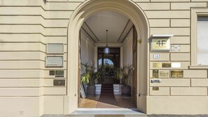 A hotel entrance with a large arched doorway, a staircase leading inside, and several plaques on the wall. - Luxury Lungarno House by MMega (Florence)