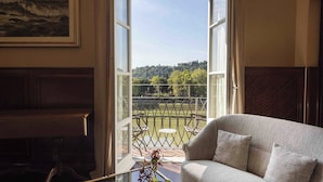 A room with a view of a balcony, a sofa, and a piano. - Luxury Lungarno House by MMega (Florence)