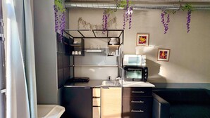 A compact kitchen with a microwave, toaster, and wooden cabinets.