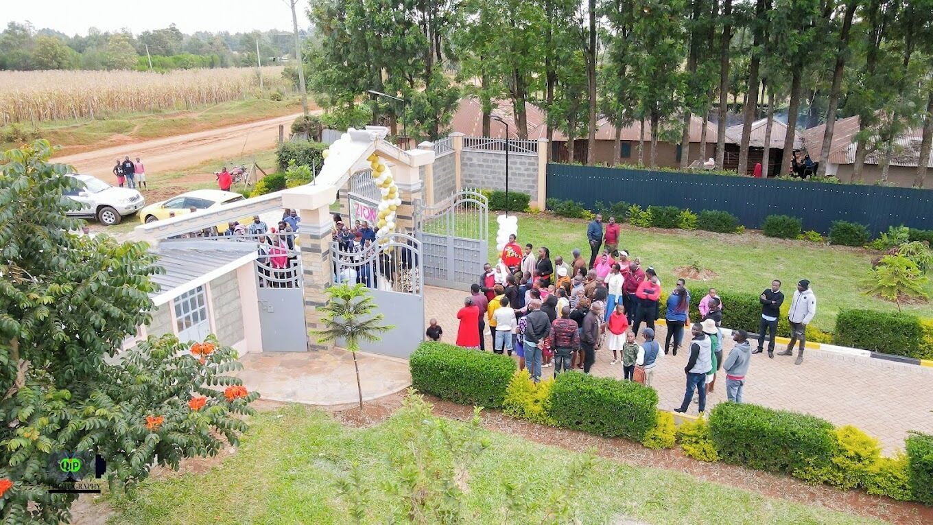 A group of people gathered near a gated entrance with a decorative archway.