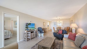 A living room with a television, seating area, and a dining table.