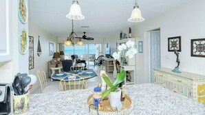 Amplia sala de estar con una gran mesa de comedor, zona de cocina y vista al océano.
