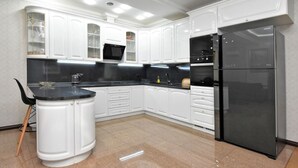 Una cocina moderna con muebles blancos, encimera negra y refrigerador negro empotrado.