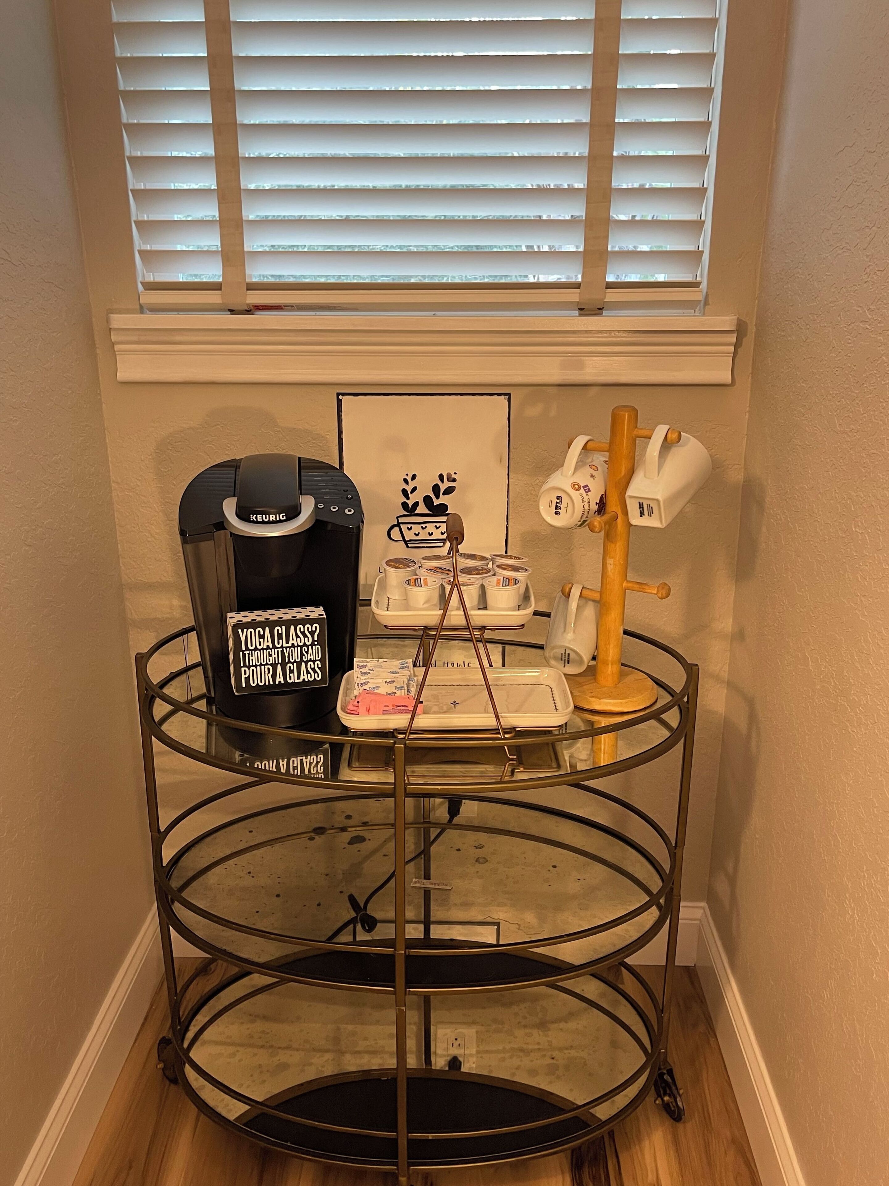 Une petite cuisine équipée d’une machine à café, d’un plateau avec des tasses et d’une autre machine à café posée sur un support en métal.