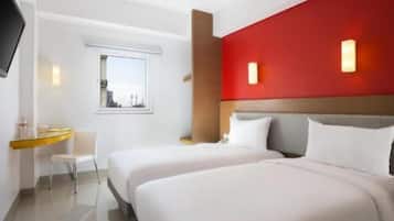 Une chambre d’hôtel avec deux lits, un bureau, une chaise, une télévision et une fenêtre.