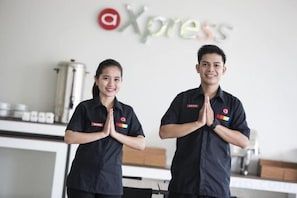 Two individuals in uniform with a logo on their shirts, standing in a room with a wall-mounted sign that reads 'Xpress'. - Amaris Hotel Hertasning (Makassar)
