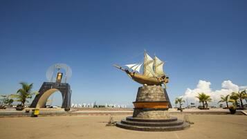 Une zone côtière où se trouve une grande sculpture représentant un navire, une arche et un panneau indiquant « PANTAI LOSARI ».