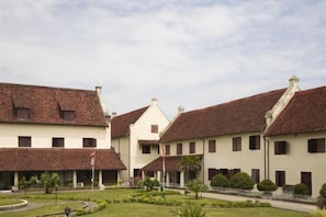 A courtyard with buildings featuring red-tiled roofs and white walls, surrounded by a white fence. - Amaris Hotel Hertasning (Makassar)