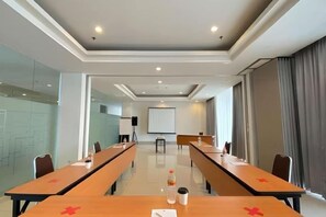 A conference room with long tables, a whiteboard, and a projector screen. - Amaris Hotel Hertasning (Makassar)