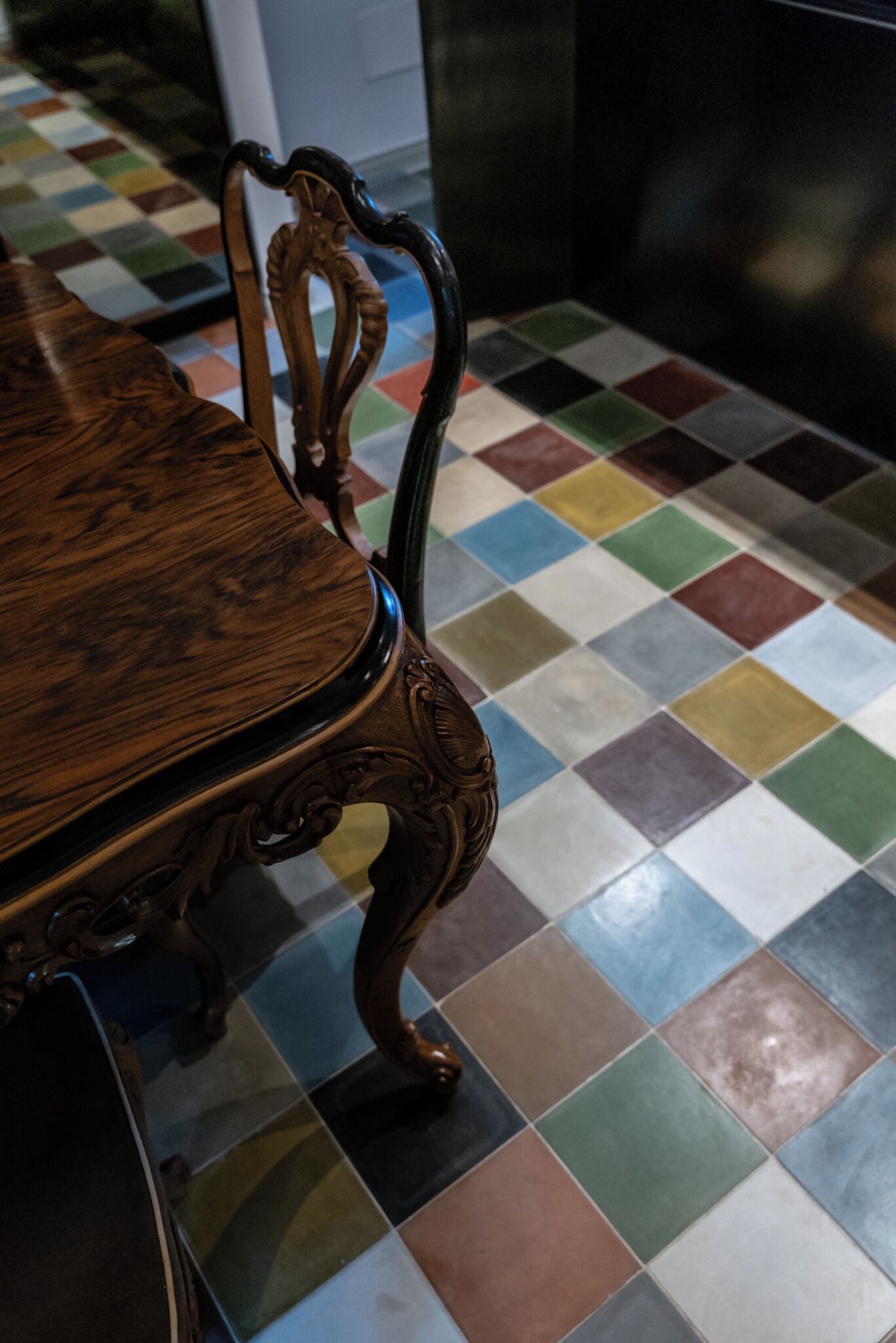 A dining table with ornate legs and a checkered floor.