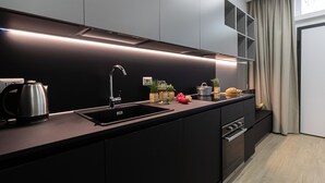 A modern kitchen with a black countertop, stainless steel kettle, and a built-in sink. - Italianway Easy - Ponte Seveso 25 (Milan)