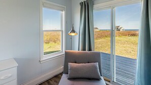 A room with a large window, a lamp, and a bench. - Shore to Sky Oceanfront Escape with Sunroom, Stunning Views & Beach Access (Prince Edward Island)