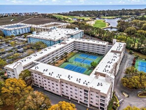 Hotel com vários andares e um pátio central com quadras de tênis.
