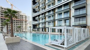 Een modern hotel met een zwembad, meerdere balkons en een bouwkraan op de achtergrond.