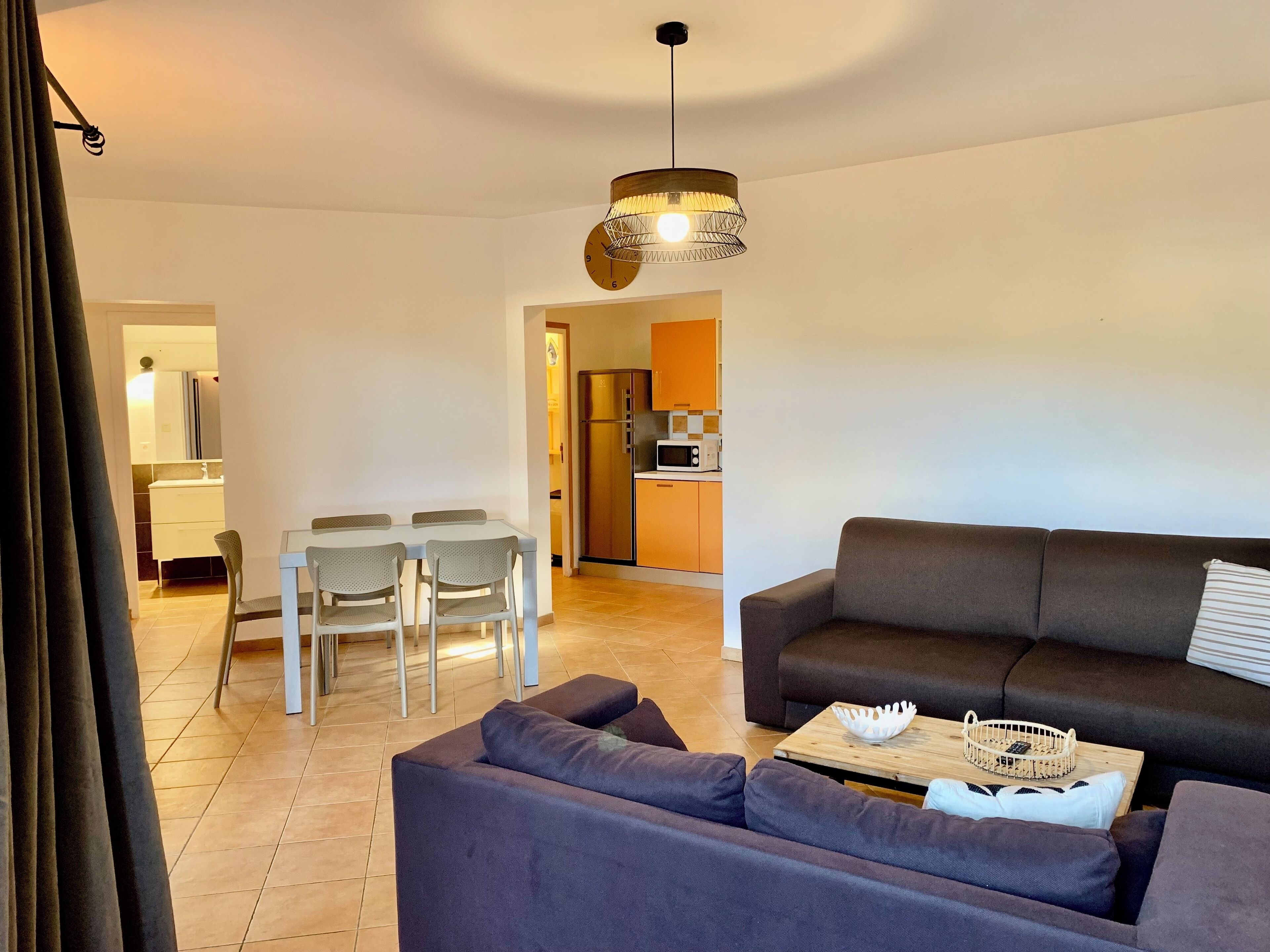 Un salon moderne avec un canapé, une table à manger et des chaises, et une cuisine en arrière-plan.