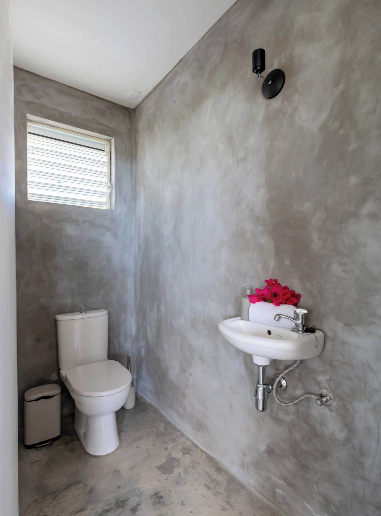 Une salle de bain avec des toilettes, un lavabo et une fenêtre.