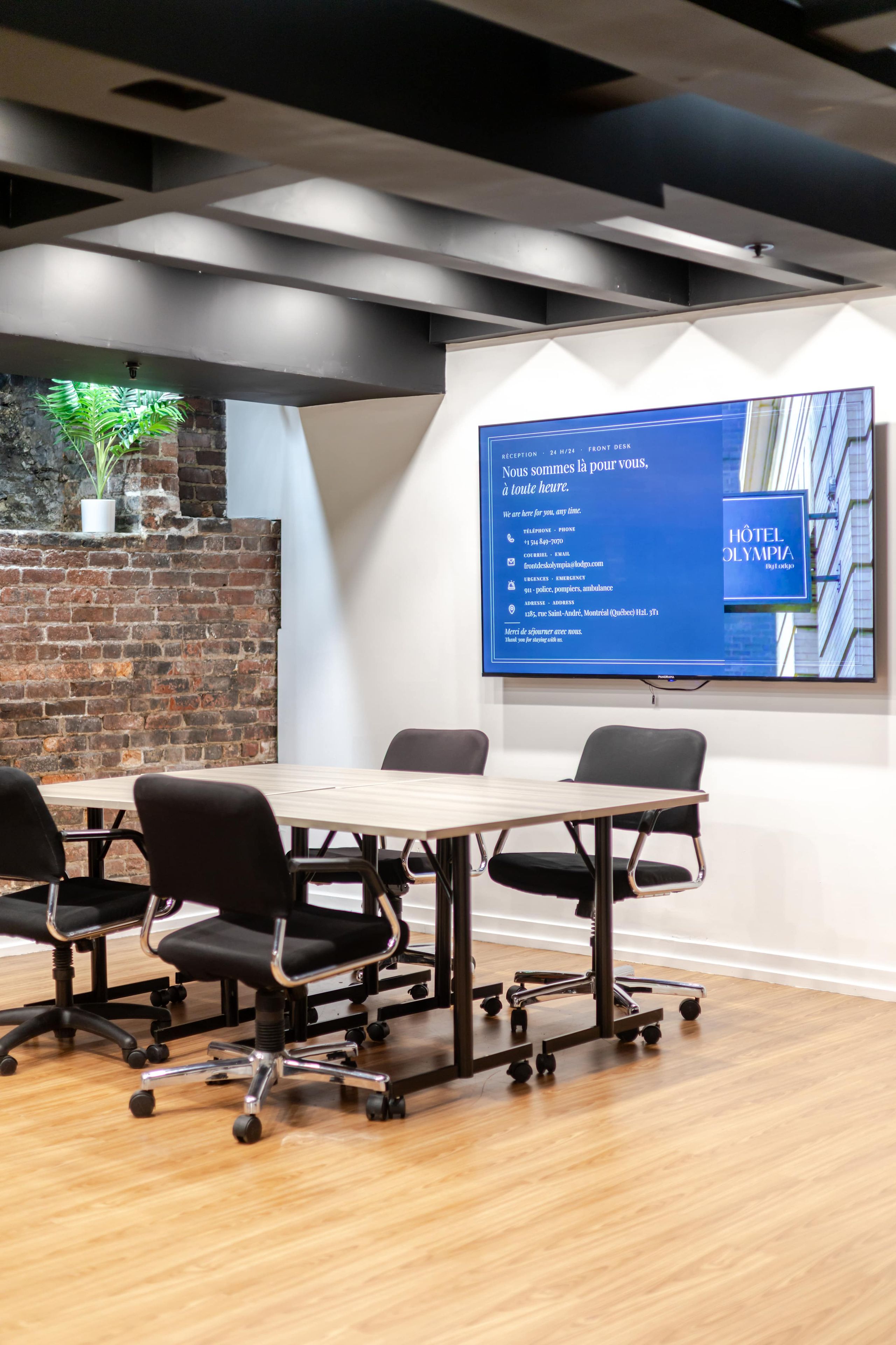A conference room with a reception desk, a potted plant, and a sign with hotel information.