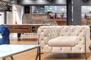 A modern living area with a tufted sofa, a glass-top table, and a wooden floor. - Private Basement Suite | Stays & Events (Montreal)