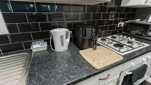 A kitchen with a gas stove, a kettle, a coffee maker, and a microwave.