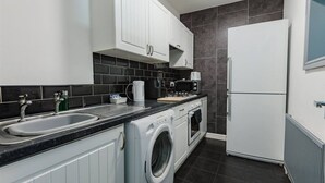 A compact kitchen with a washing machine, a microwave, and a refrigerator.