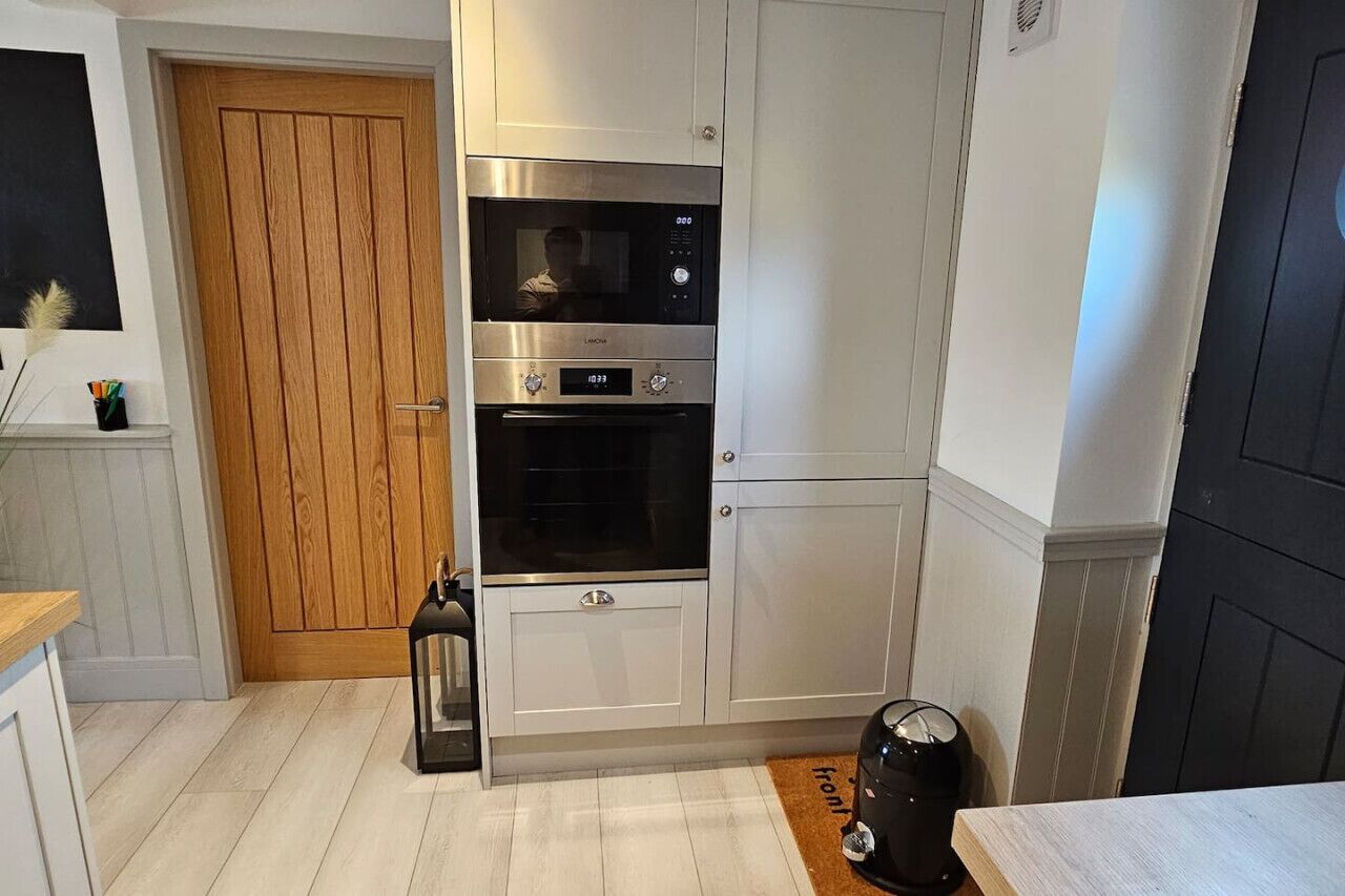 A kitchen with stainless steel appliances, a wooden door, and a black lantern on the floor.