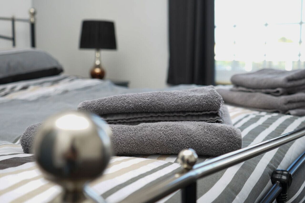 Een net opgemaakt bed met gestreepte lakens en een metalen hoofdbord.