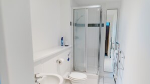 Et moderne badeværelse med toilet, vask og brusekabine med glasvægge.