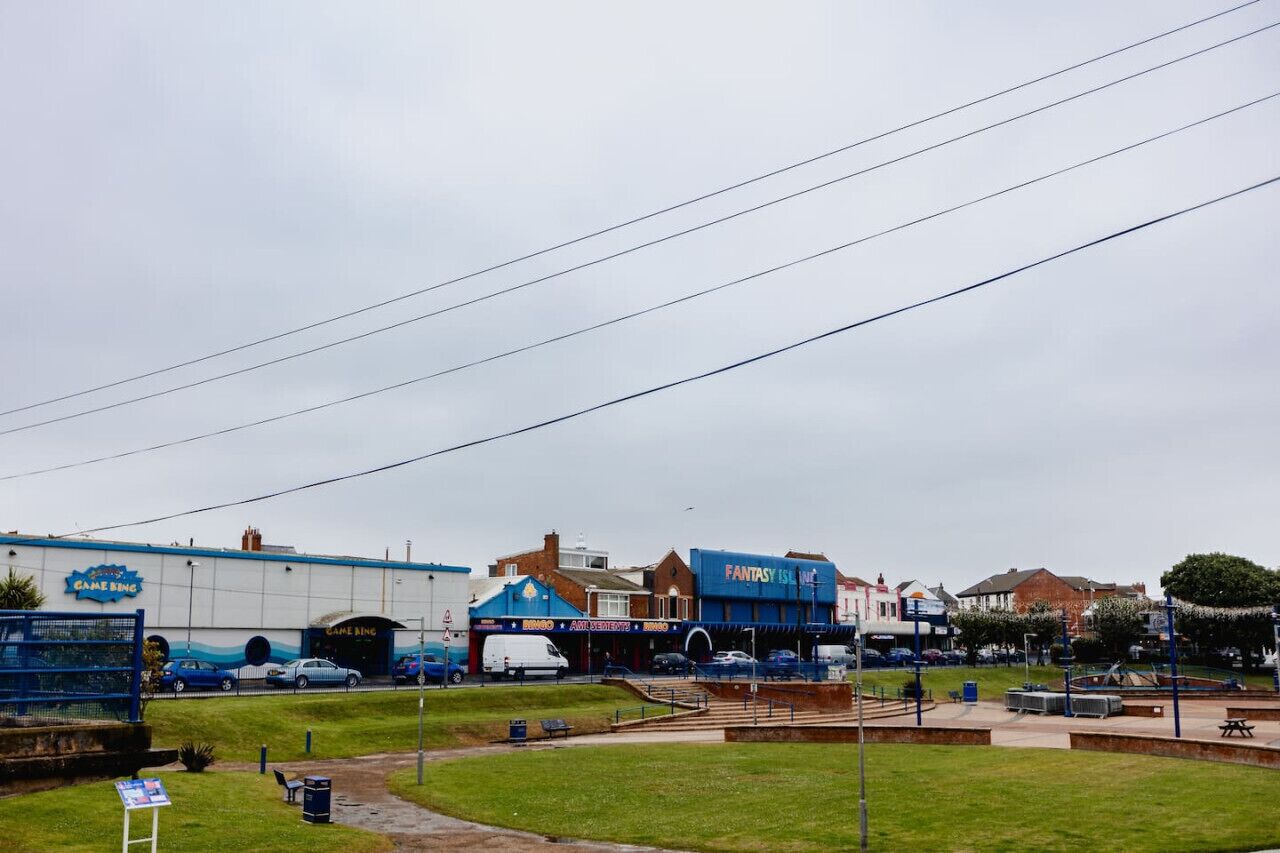 A parking lot with several cars and a white van, a blue building labeled "GAME BING," and a blue building labeled "FANTASY ISLAND."
