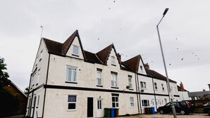 A two-story residential building with a symmetrical facade, multiple windows, and a visible front door. - Withernsea Studio Apt + Sofa bed (Withernsea)