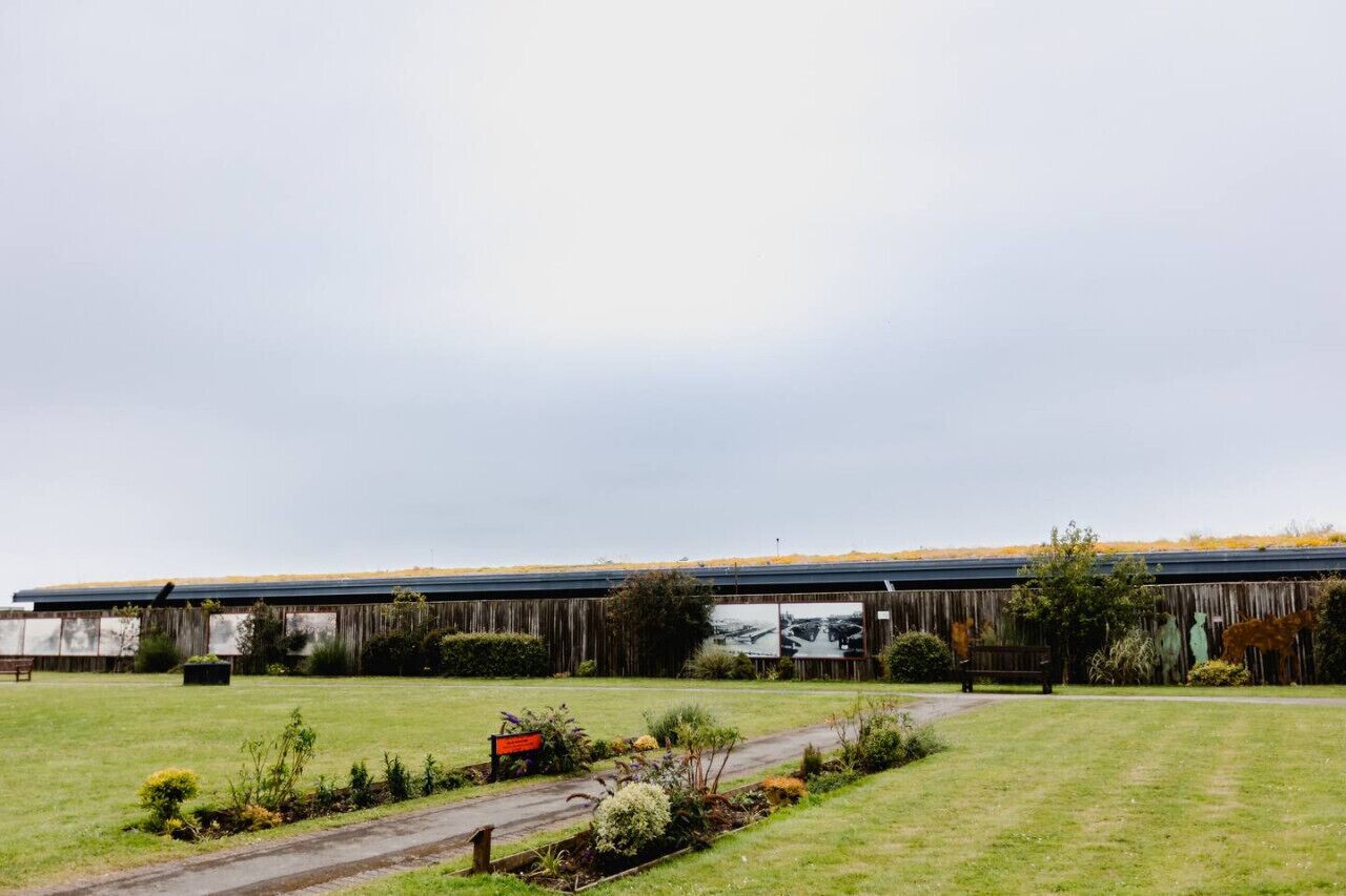 A large building with a flat roof, surrounded by a grassy area with a pathway leading to it.