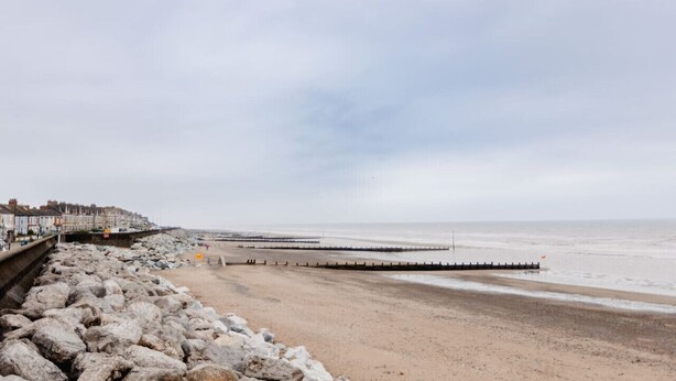 A beach with a rocky shoreline, a pier extending into the sea, and a row of buildings along the coast. - Withernsea Studio Apt + Sofa bed (Withernsea)