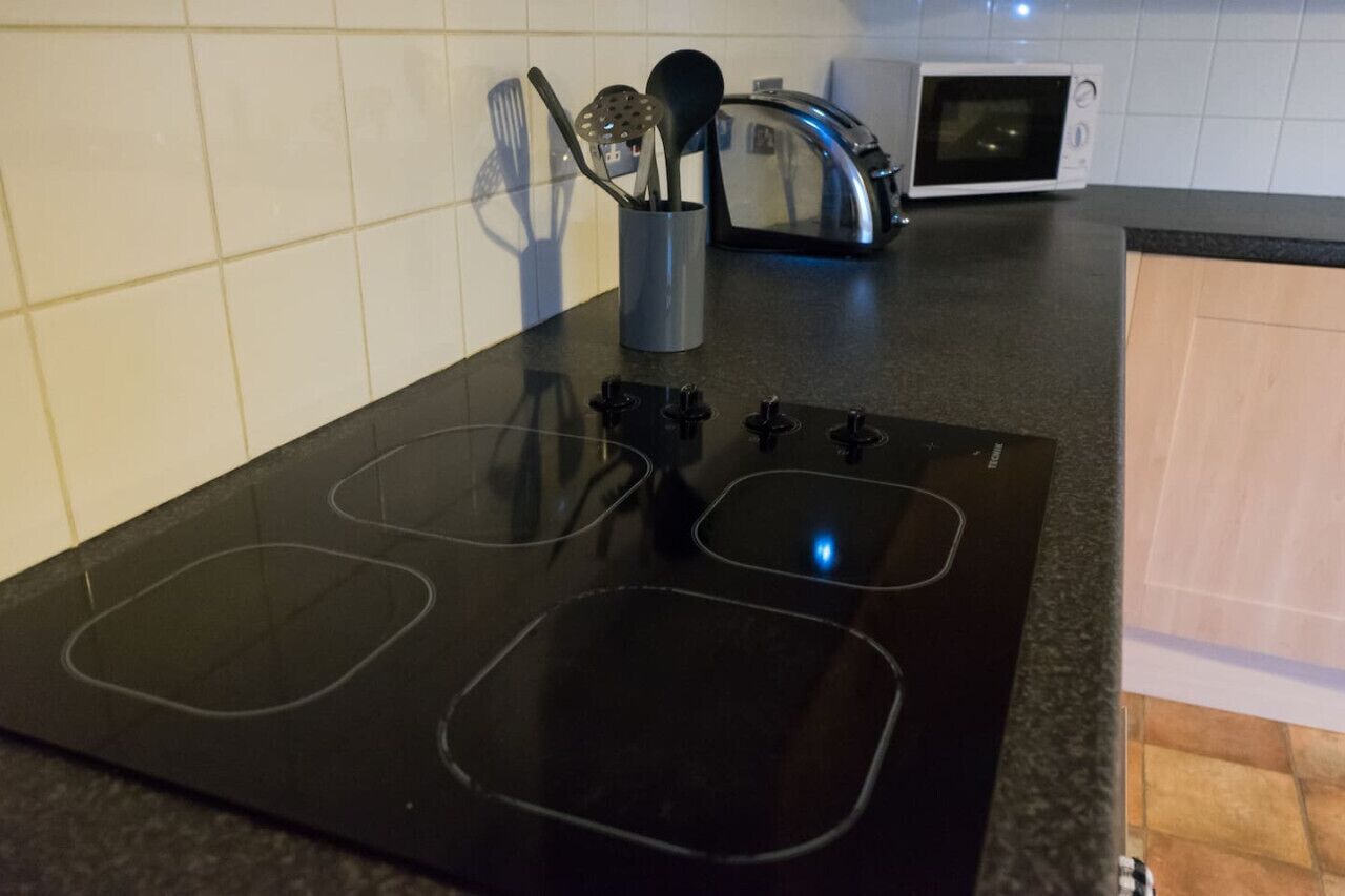 A kitchen with a black induction cooktop, a toaster, and a microwave.