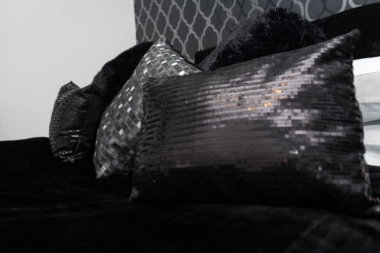 Een bed met zwart-zilveren kussens en een bedombing met patroon.