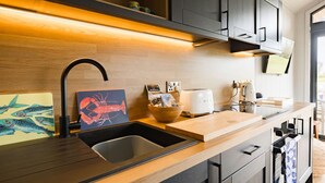 A modern kitchen with a wooden countertop, a black faucet, a toaster, and a bowl of snacks. - Lowfield Lodge & Hot Tub (Humberston Fitties Cleethorpes)