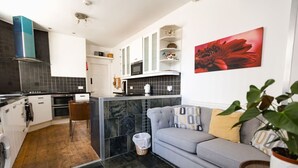 Una cocina moderna con un sofá gris y un cuadro de una flor roja.