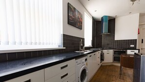 Una cocina moderna con lavadora incorporada, un ventanal con persianas y un cuadro en la pared.