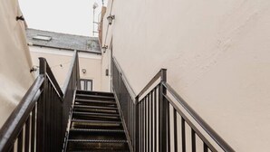A narrow stairway with metal railings and a textured floor, leading to a higher level.