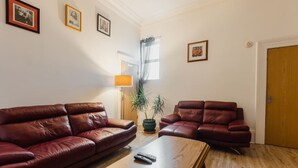 A living room with two leather sofas, a wooden coffee table, and a potted plant.