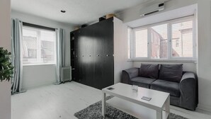 Un salon moderne avec un canapé gris, une table basse blanche et une armoire noire.